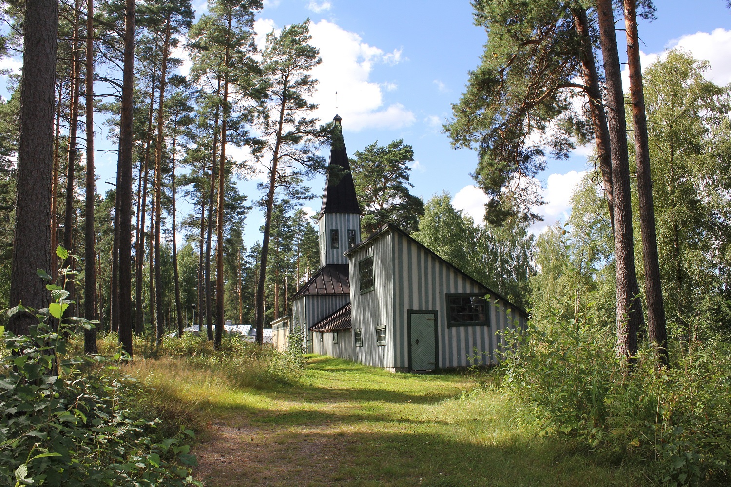 pieni harmaa kirkko metsässä