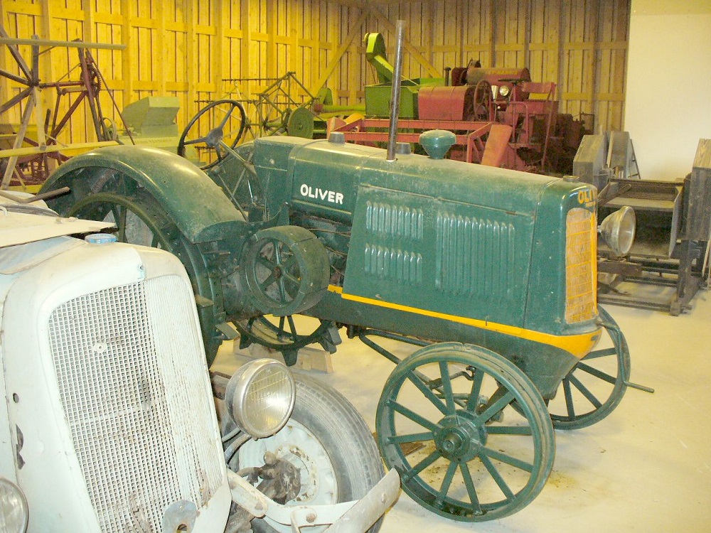 vanhoja traktoreita ja maatalouskoneita. Keskellä vihreä Oliver-traktori.