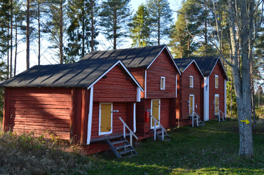 neljä punamultamaalattua hirsiaittaa rivissä